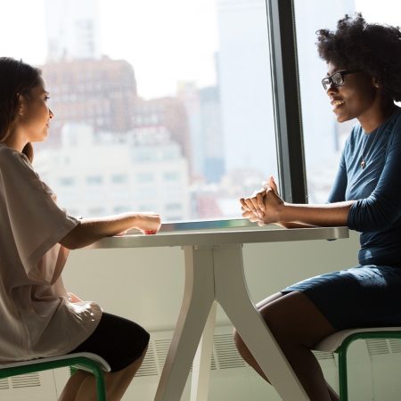 Fotografía de dos mujeres sentadas y charlando frente a frente en una mesa pequeña. Imagen de user1505195587 en Pixabay. (Español) / Fotografia de duas mulheres sentadas conversando frente a frente em uma pequena mesa. Imagem de user1505195587 no Pixabay. (Português) / Photograph of two women sitting and chatting face to face at a small table. Image by user1505195587 on Pixabay. (English)