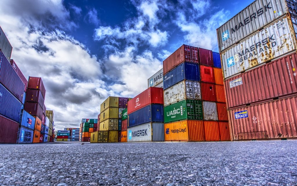 Photograph of a series of containers on an asphalt floor and under a blue sky with clouds. Image by Markus Distelrath on Pixabay. (English) / Fotografía de una serie de contenedores sobre un piso asfaltado y bajo un cielo azul y con nubes. Imagen de Markus Distelrath en Pixabay. (Español) / Fotografia de uma série de contêineres em um piso de asfalto sob um céu azul e nublado. Imagem de Markus Distelrath no Pixabay. (Português)