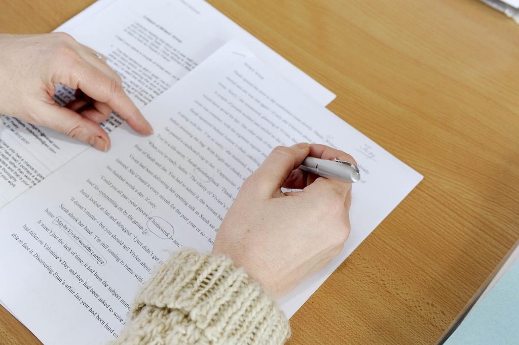 Photograph of a woman proofreading a text in first-person view. Image by Wokingham Libraries at Pixabay. (English) / Photograph of a woman correcting a text in first-person view. Image of Wokingham Libraries on Pixabay. (Português) / Photograph of a woman proofreading a text, first-person view. Image by Wokingham Libraries on Pixabay. (Español)
